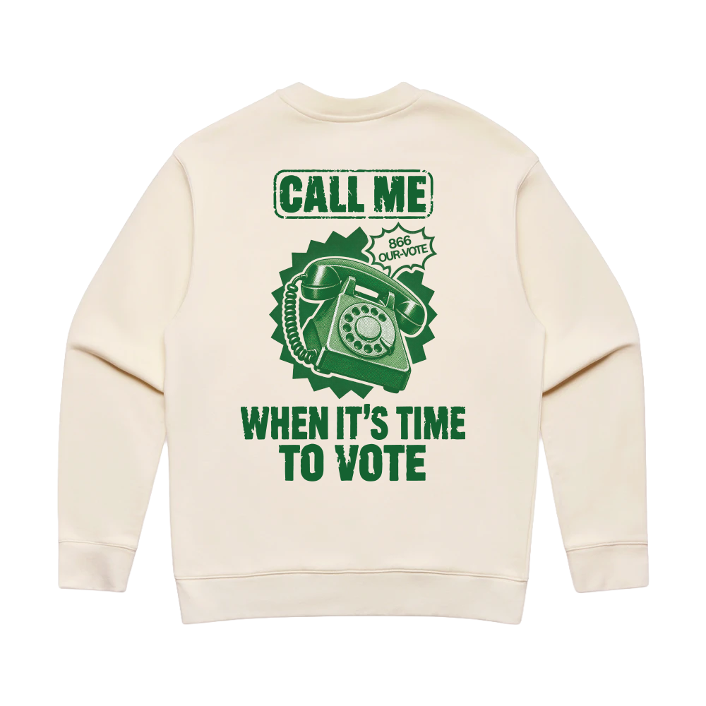 An off-white crewneck sweatshirt shown from the back, featuring a green graphic print of a rotary telephone with the text 'CALL ME WHEN IT'S TIME TO VOTE' and a badge reading 'BIG COURAGE'.